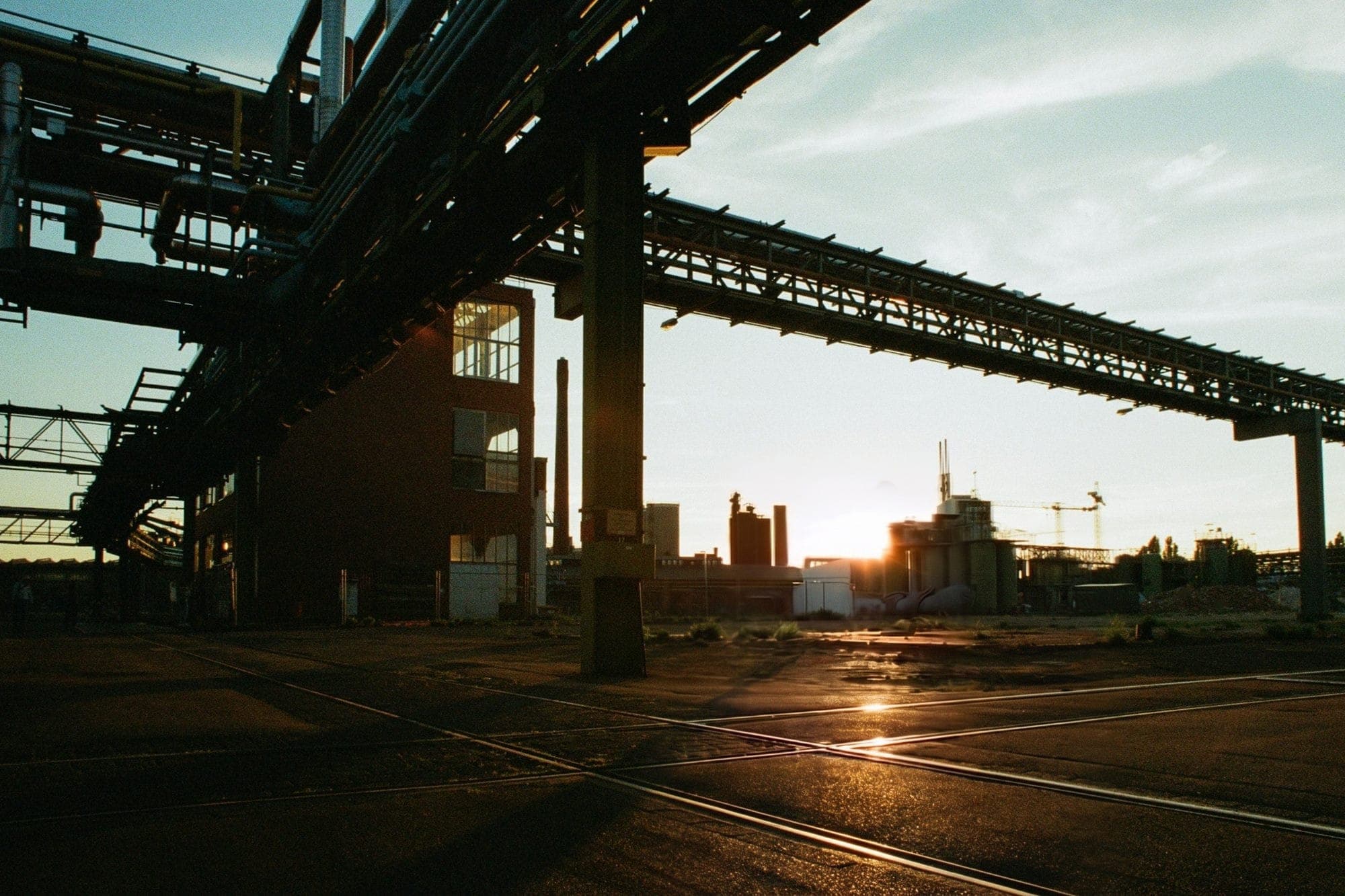 Plant pipe racks over an empty yard at sunset